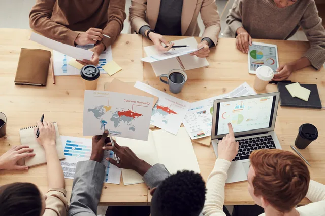 Diverse team engaging in a collaborative meeting with charts and laptops. What the AI marketing tools advertising rules mean for campaign sign-off
