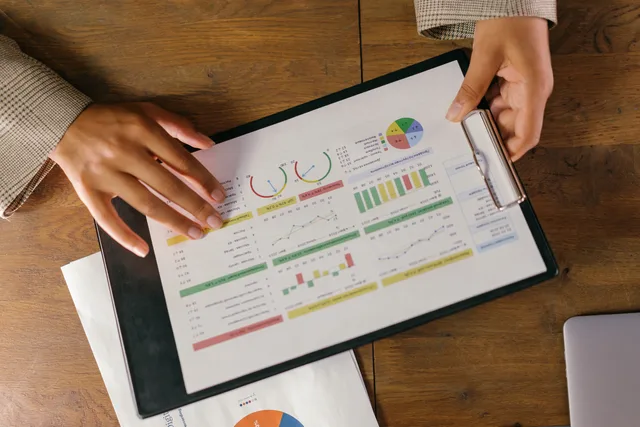 Top view of hands holding a financial report with colorful graphs and charts, ideal for business presentations. AI marketing tools: how to assess vendor scorecards