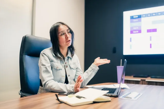 Businesswoman explaining a concept during a meeting with a presentation displayed on screen. How to test a borrowed benchmark for AI marketing tools
