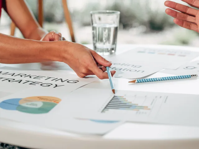 Hands discussing marketing strategy with charts in an office setting. Run the AI marketing tools market entry checklist before you launch