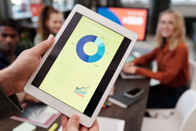 Business team reviewing digital marketing statistics on a tablet during an indoor meeting. Nine steps to a more realistic AI marketing tools outlook